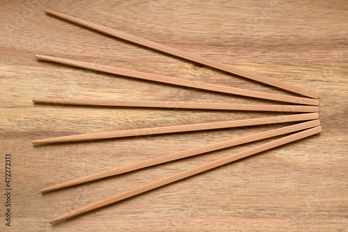 Top view of bamboo chopsticks fanning out against a wooden board, close up