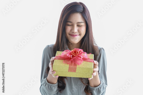 Happy New Year, Christmas and Holiday Seasonal Concept. Portrait of young asian smiling woman close eye and holding a beautiful gift box.