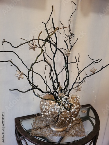 Bouquet de branchages dans vase doré avec guirlandes lumineuses 