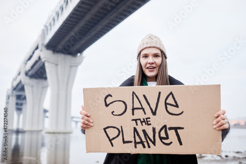 Portrait of young woman holding signs and shouting while protesting at environmental disaster site