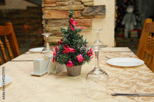 Christmas table setting with christmas tree and wooden chairs in russian restaurant interior © Ilya