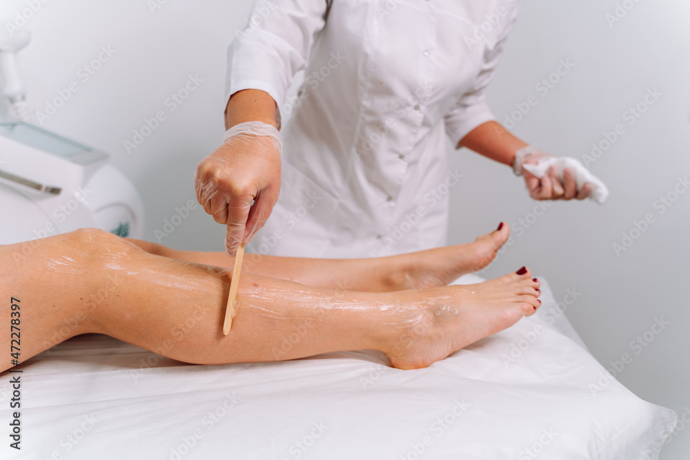 Fototapeta premium Laser epilation and cosmetology in beauty salon. Laser hair removal, skin care. Top view of woman legs during laser hair removal procedure