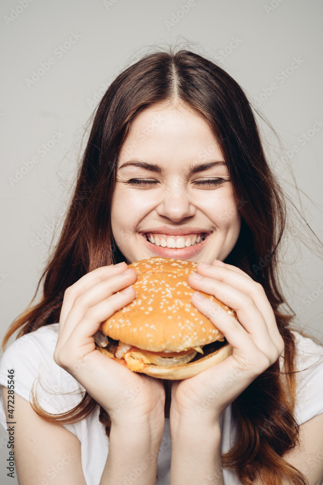 woman with a hamburger in her hands a snack fast food close-up woman with a hamburger in her hands a snack fast food close-up