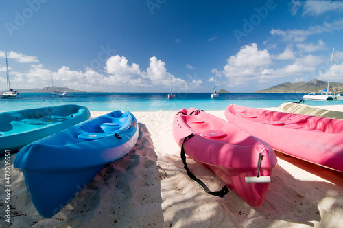 Colorful kayaks on tropical sandy beach. Boats for rafting on water. White sand, turquoise ocean water and blue sky at exotic Palm Island. Saint Vincent and Grenadines, West Indies photo