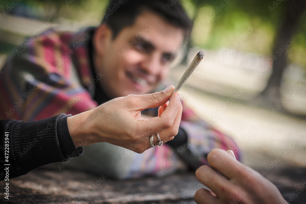 Closeup view of marijuana joint circling around hand to hand Closeup view of marijuana joint circling around hand to hand