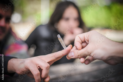 Closeup view of marijuana joint circling around hand to hand