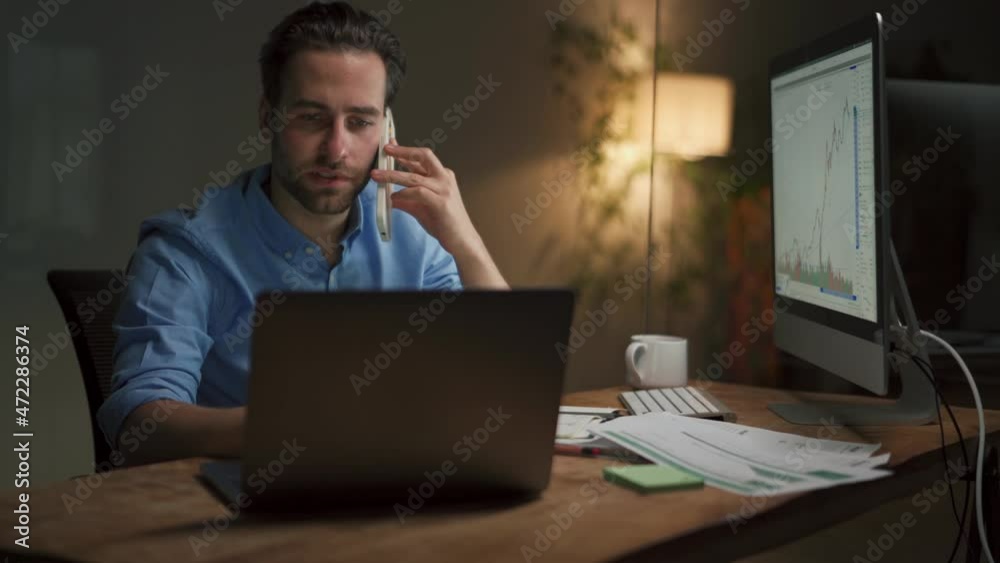 Sad man talking by phone and looking at the investment schedule in office Sad man talking by phone and looking at the investment schedule in office