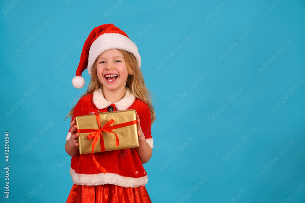 Happy merry Christmas child in Santa hat hold gift. beautiful girl smiles laughs. Congratulate celebration. Jolly Santa Claus preparing box gold red bow. Happy New Year. Place for text. Copy space. Happy merry Christmas child in Santa hat hold gift. beautiful girl smiles laughs. Congratulate celebration. Jolly Santa Claus preparing box gold red bow. Happy New Year. Place for text. Copy space.