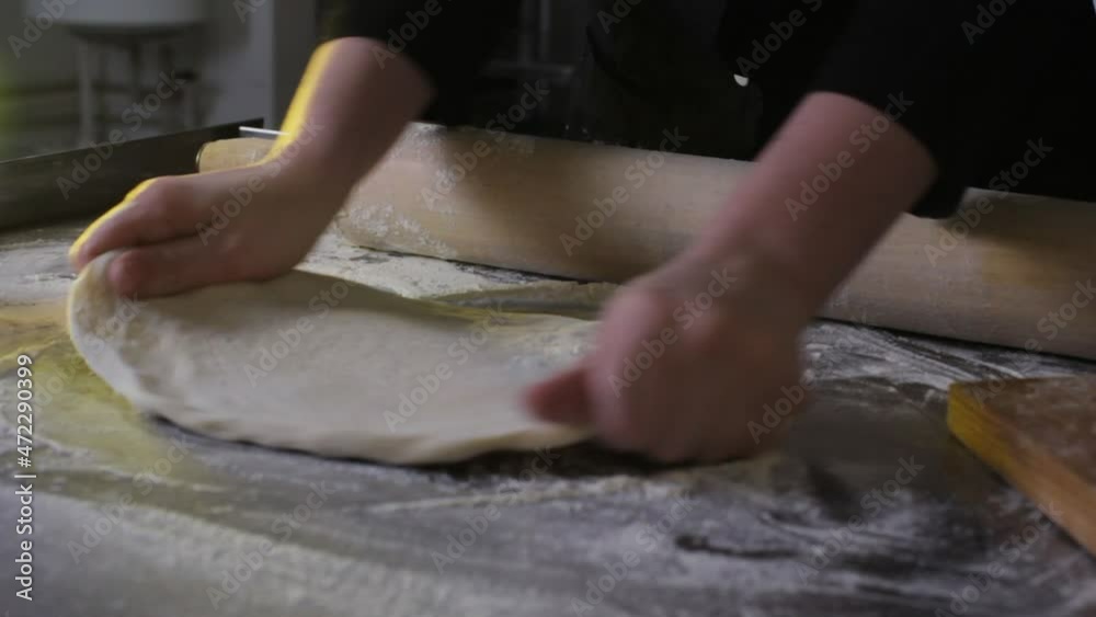 A professional chef stretches and twists soft Italian pizza dough with his hands. close-up A professional chef stretches and twists soft Italian pizza dough with his hands. close-up