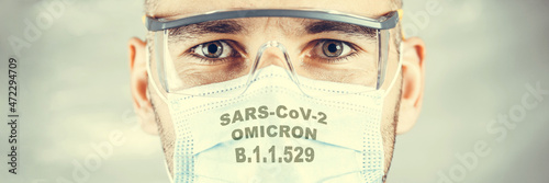New African variant of the coronavirus. Mask on the mans face with the inscriptions SARS COV 2 Omicron. Wide banner. photo