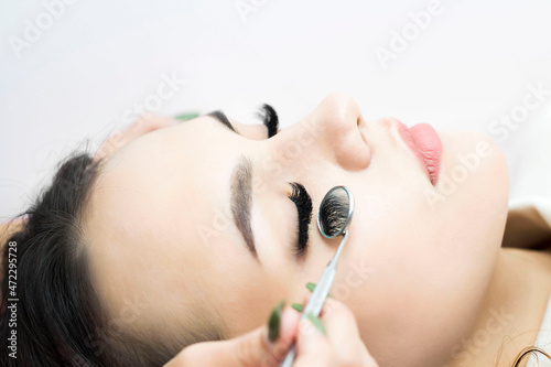 Eyelash extension procedure. Beautiful woman with long eyelashes in a beauty salon. The eyelashes are closing. a mirror in the hands of a master