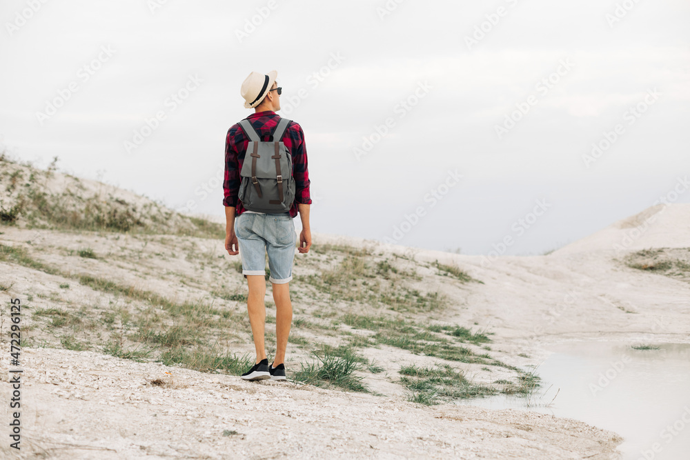man with a backpack walking along the sandy rocky mountains. Summer expedition vacation outdoors