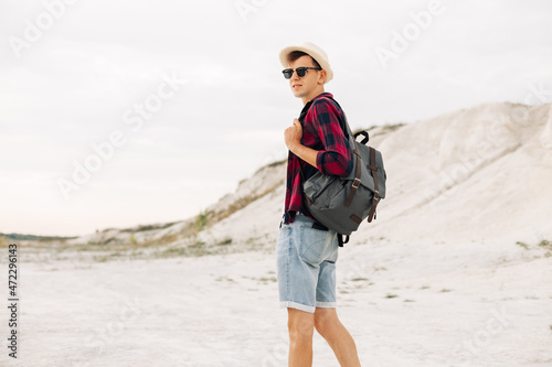man traveler in a hat and with a backpack walks along a mountain road, man travel hiking in the Scandinavian mountains © Shopping King Louie