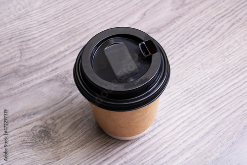 Paper cup with coffee on wooden background