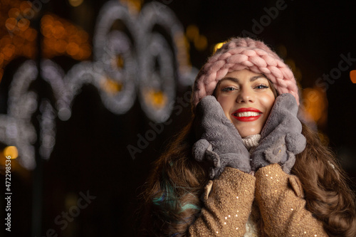 Merry lady in pink hat walking in the evening street