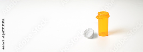 Empty prescription bottle with lid off on white background