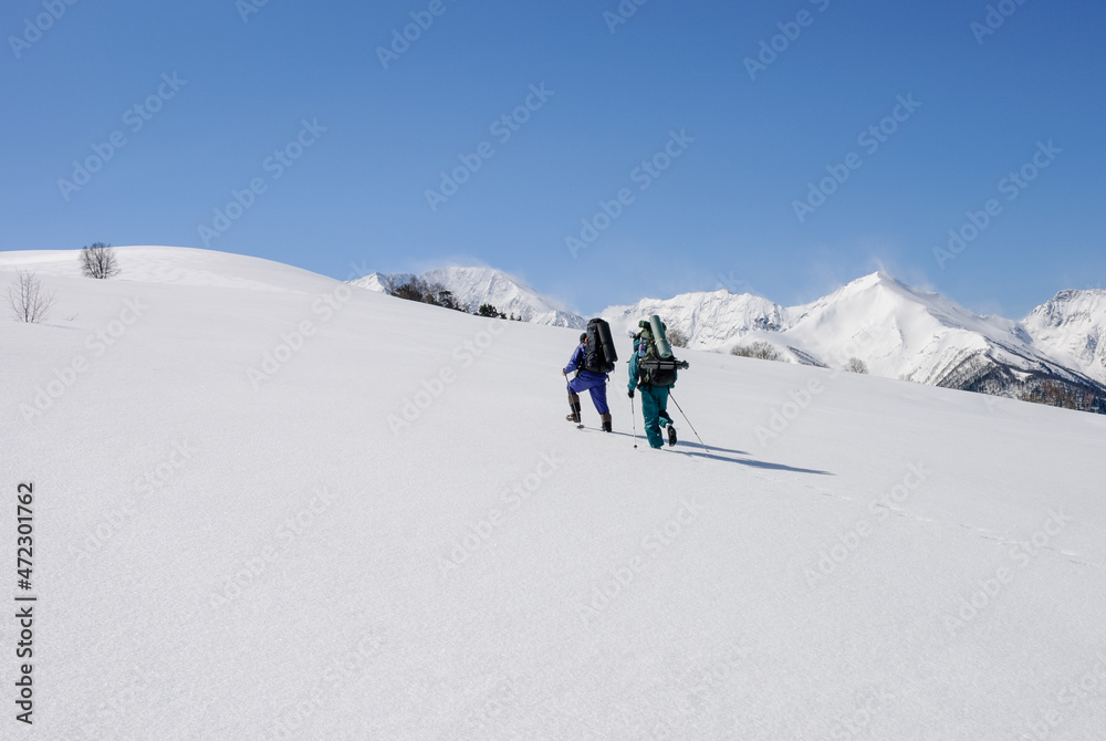 tourists with backpacks climb the snow uphill