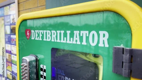 Brightly coloured defibrillator cabinet installed on a city street in the UK, allowing members of the public to assist with medical treatment in the event of a cardiac emergency. photo