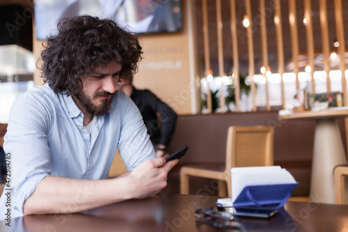 Man at a modern cafe looking at phone.