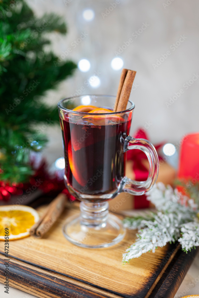 delicious hot spicy red mulled wine with orange and cinnamon spices near the Christmas tree with decorations and bokeh garlands delicious hot spicy red mulled wine with orange and cinnamon spices near the Christmas tree with decorations and bokeh garlands