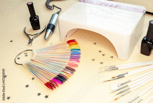 Manicure and pedicure cosmetics on a beige background, copy the space. Varnishes, nail clippers, manicure machine, lamp, brushes for home and salon procedures