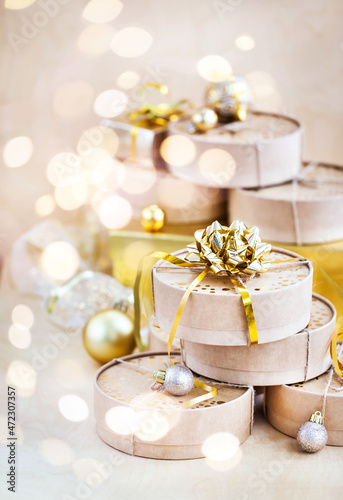 Christmas or New year round kraft gift boxes, gold holiday balls on a bokeh background of twinkling party lights of garland