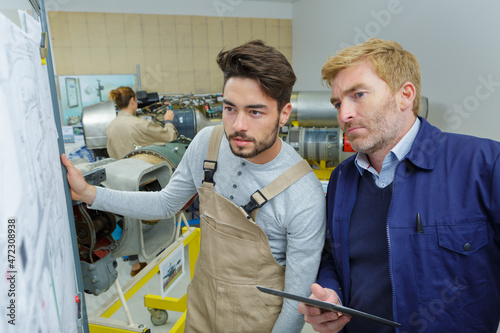 two young creative engineers working on drawing board photo