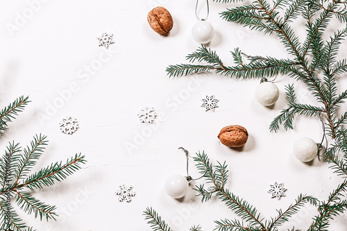 Minimalistic Christmas background. Spruce branches, walnuts and snowflakes on a white background