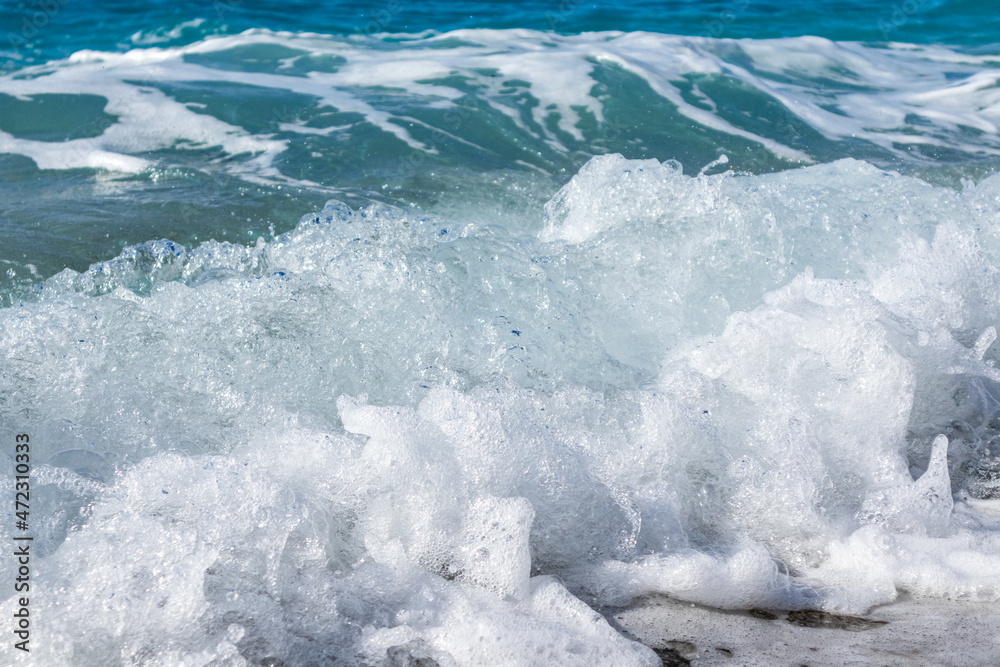 Shining waves splash close-up with white foam. Clear blue water on Island in Greece. Summer travel to Ionian Sea