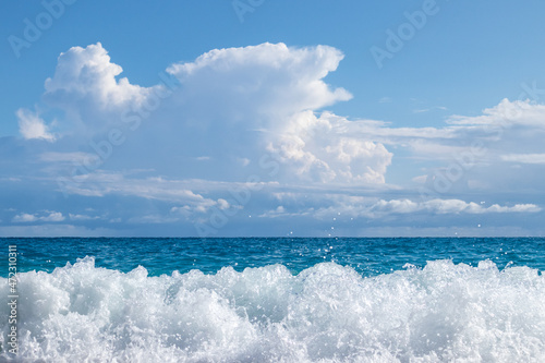 Shining waves splash with white foam. Blue stormy sea and epic clouds on coast of Lefkada island in Greece. Summer travel to Ionian Sea