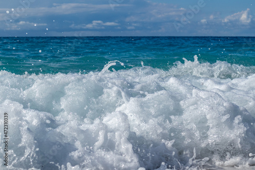 Shining waves splash with white foam drops. Blue vivid sea and epic clouds on coast of Lefkada island in Greece. Summer travel to Ionian Sea © Kathrine Andi