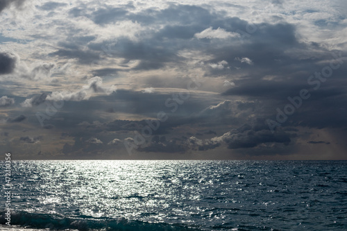 Epic dark sea shining with sun beam with blue cloudscape on beach, island in Greece. Summer scenery of Ionian Sea