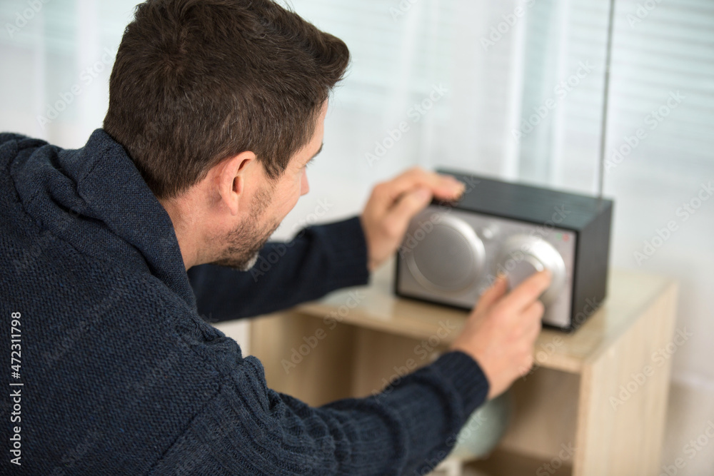 Fototapeta premium man adjusting volume on wireless speaker at home