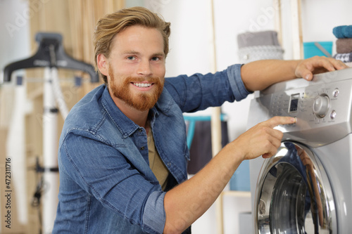 man pressing button to start washing machine © auremar