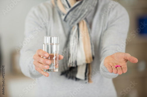 male holding pills in hand and glass of water