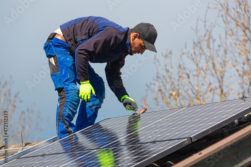 Installing solar photovoltaic panel system. Solar panel technician installing solar panels on roof. Alternative energy ecological concept.