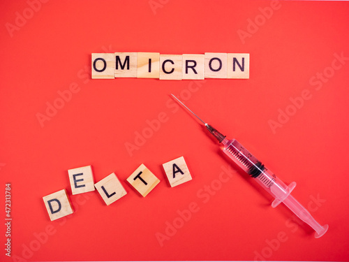 Omicron variant replaces Delta. Emergence of new dangerous strain of coronavirus COVID-19 Omicron. Syringe. Words omicron delta on colored red background photo
