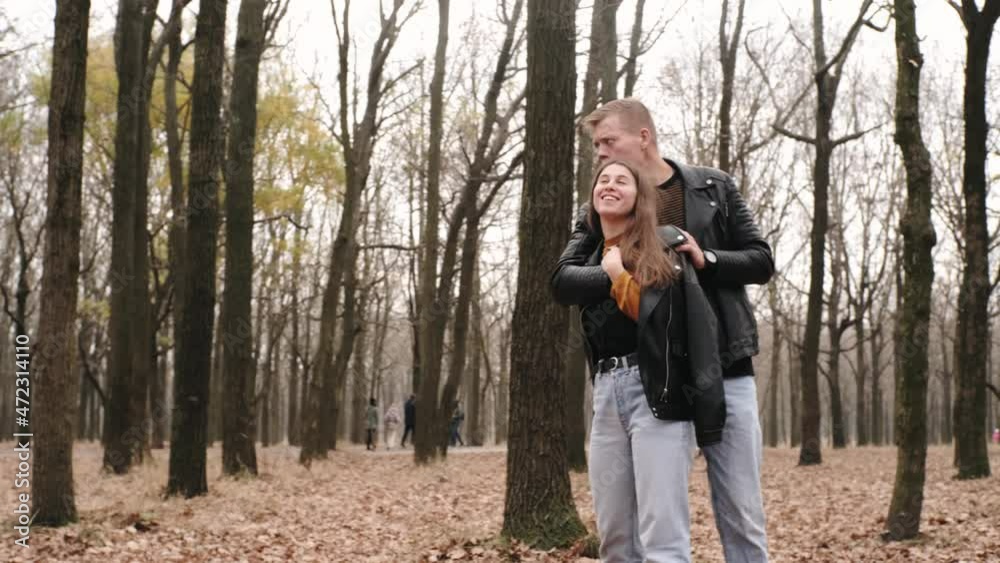 Happy young couple in love walking in autumn park, hugging, kissing and having fun Happy young couple in love walking in autumn park, hugging, kissing and having fun