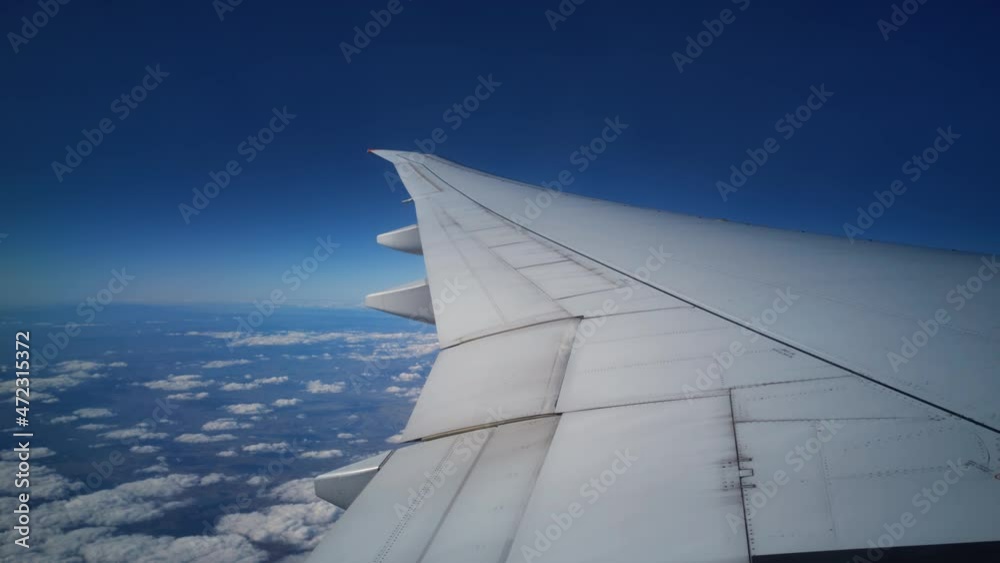 View from the plane window on its wing and the earth under cloudscape. Flying jet filmed from inside. Air transportation theme. Travelling in different countries by sky vehicles. Voyage on an altitude View from the plane window on its wing and the earth under cloudscape. Flying jet filmed from inside. Air transportation theme. Travelling in different countries by sky vehicles. Voyage on an altitude
