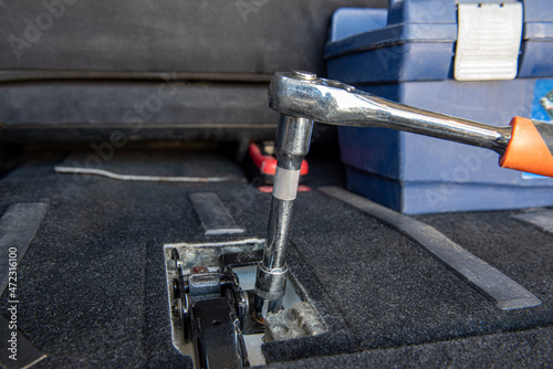 A man's hand unscrews the nut in the car interior with a ratchet. Specialist Unscrews Bolts Close-up