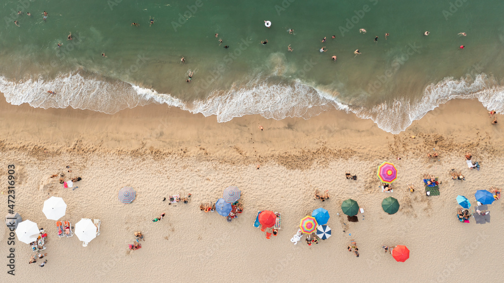 Playa, sombrillas y gente en el mar. Top view.