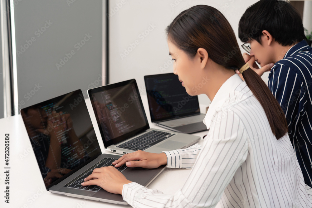 co-working concept the woman in white striped shirt working in front of laptops with her colleague, the man in black striped shirt co-working concept the woman in white striped shirt working in front of laptops with her colleague, the man in black striped shirt