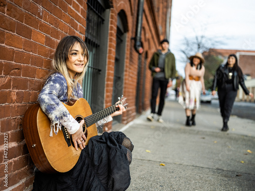 Young female Indigenous artist playing guitar outdoors photo