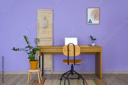 Interior of room with comfortable workplace near color wall