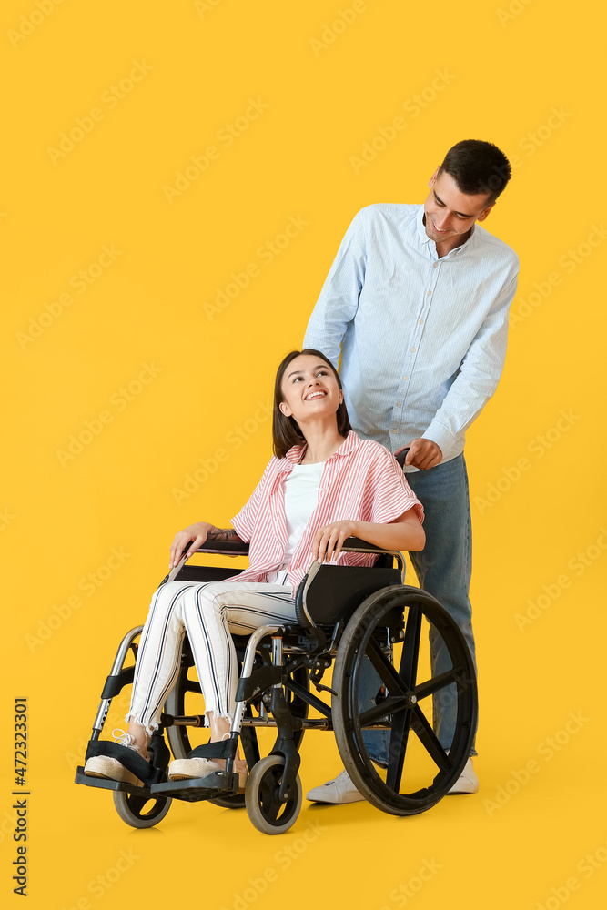 Young woman in wheelchair and her husband on color background Young woman in wheelchair and her husband on color background
