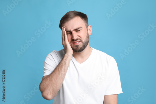Photos Young man suffering from headache on light blue background