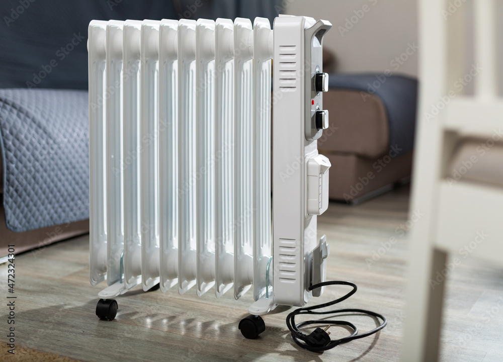 White metal portable oil heater standing in home room. Electric appliance  for heating house.. Stock Photo | Adobe Stock