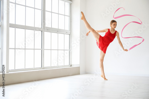 Fototapeta Naklejka Na Ścianę i Meble -  Beautiful young woman doing gymnastics with ribbon in gym