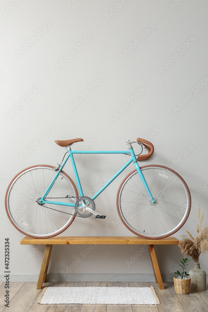 Modern bicycle on wooden bench near light wall Modern bicycle on wooden bench near light wall