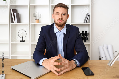 Handsome young businessman sitting at table in office